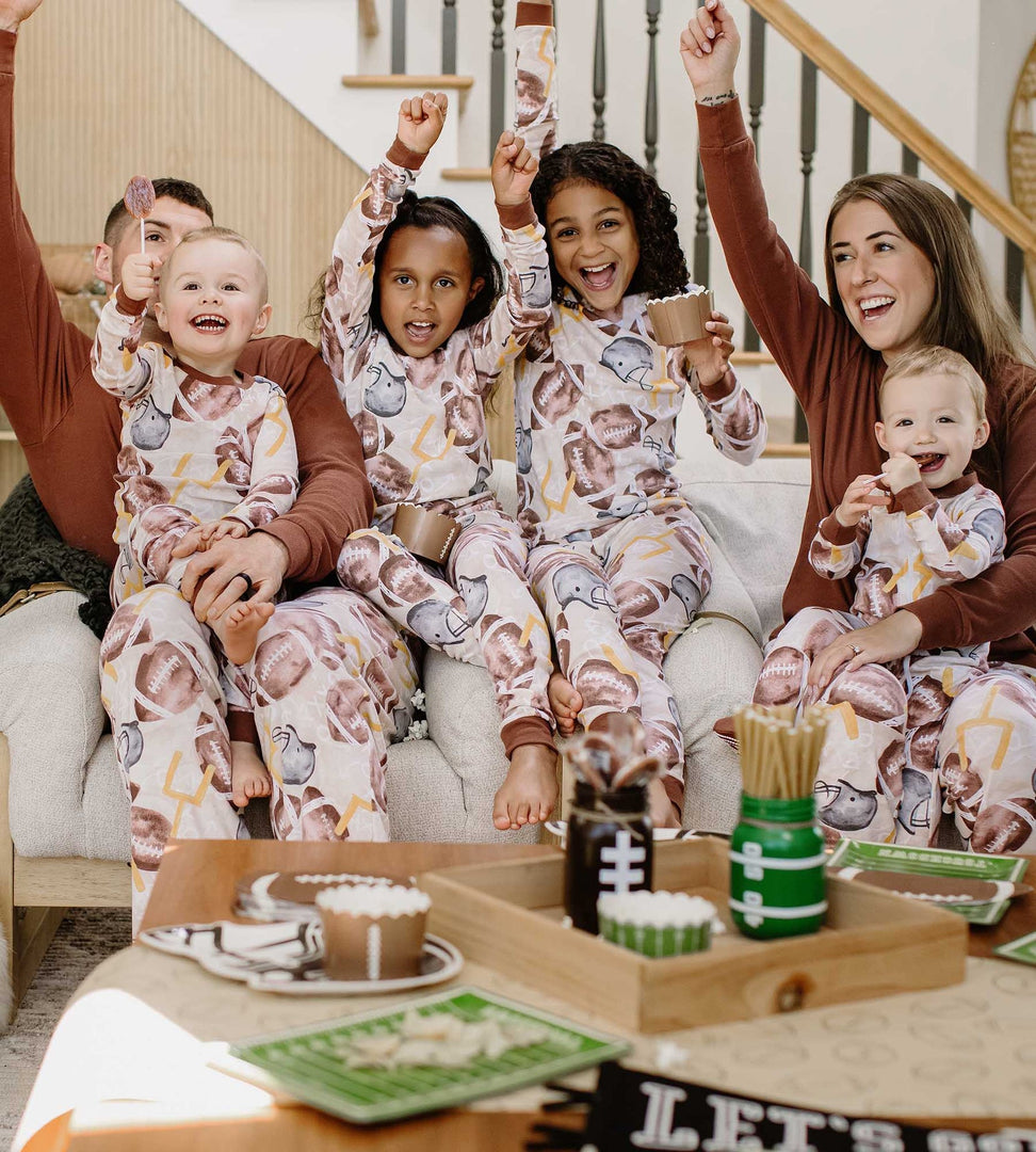 Family sitting on the couch celebrating while wearing Burt's Bees Baby matching football pajamas