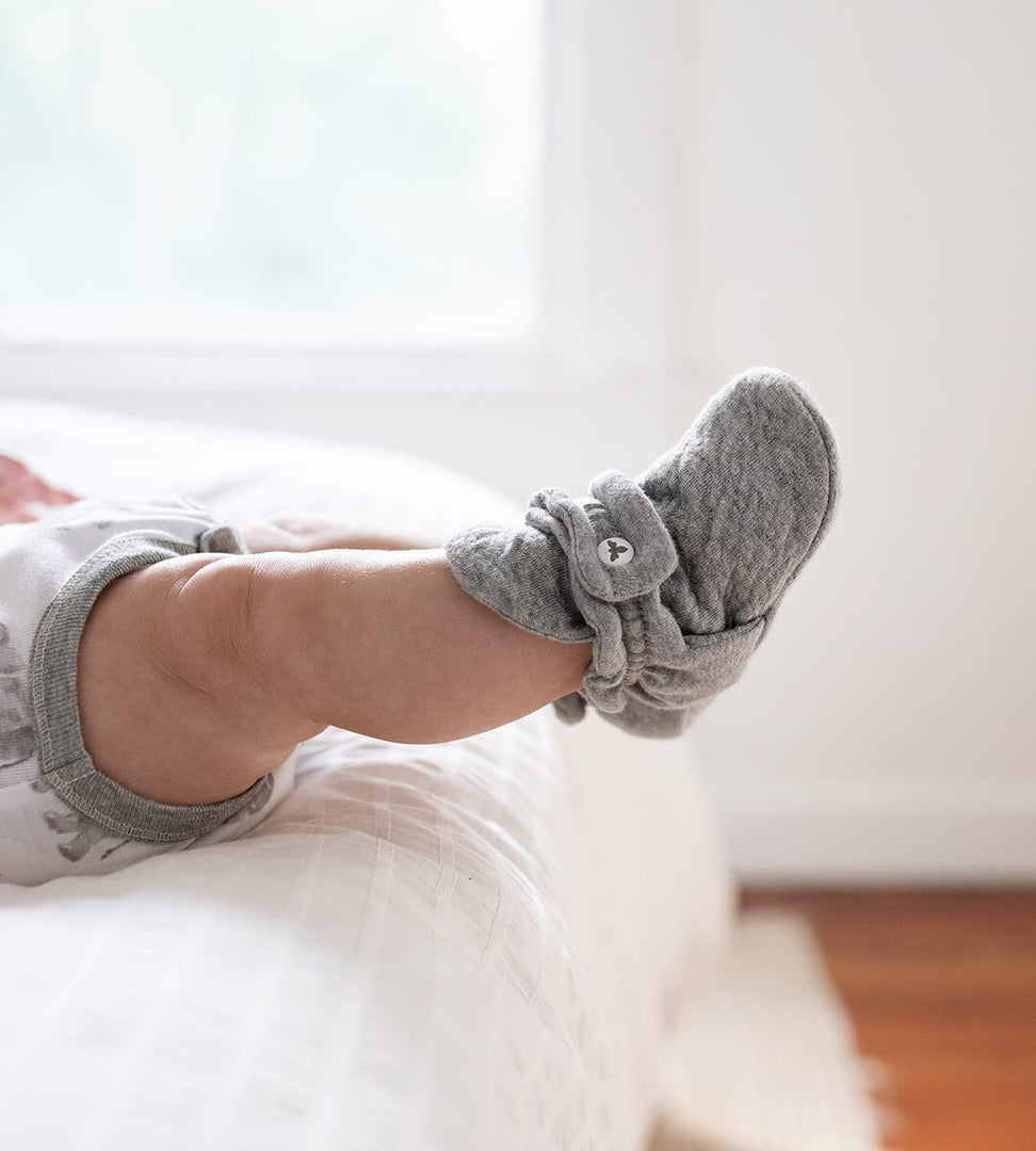 Infant laying down wearing bodysuit and Quilted Bee Grey Organic Baby Booties